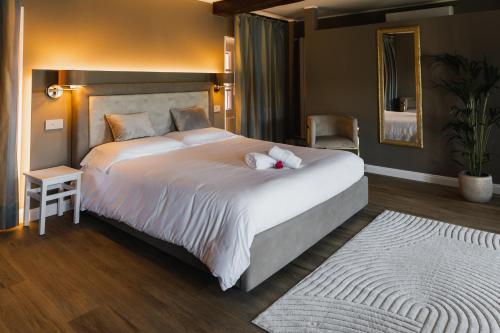 a bedroom with a large white bed and a mirror at Villa Antica Colonia SPA & Wellness in Pettenasco