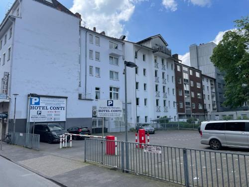 a white building with cars parked in a parking lot at Hotel Horstmann Münster in Münster