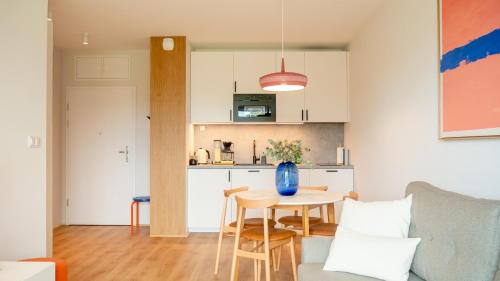 a living room with a table and a kitchen at Apartament RAINBOW SurfingBird Dźwirzyno in Dźwirzyno