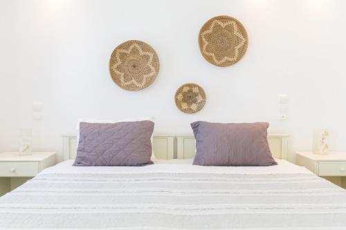Cama blanca con almohadas y platos morados en la pared en Alexandros Apartments, en Naousa