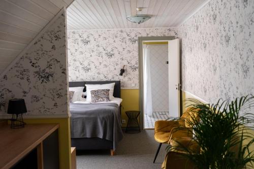 a bedroom with a bed and a yellow chair at Vanalinna Boutique Hotel in Kuressaare