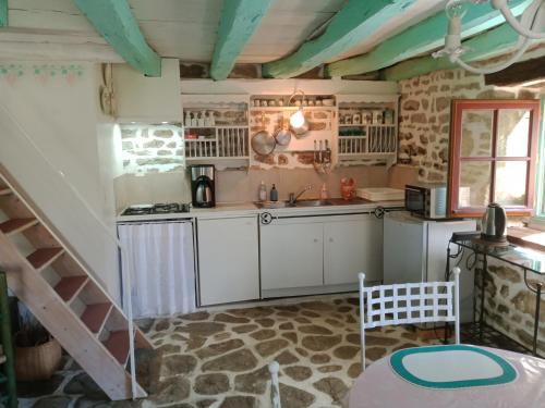 uma cozinha com armários brancos e uma escada num quarto em Gîte d'Alexandre 