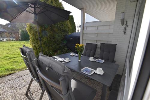 a table with chairs and an umbrella on a patio at FeWo Kiek-mol-wedder-in Whg5 in Dahme
