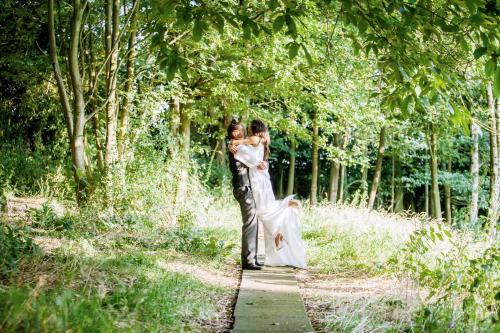 a bride and groom standing on a path in the woods at The Upper House in Stoke on Trent