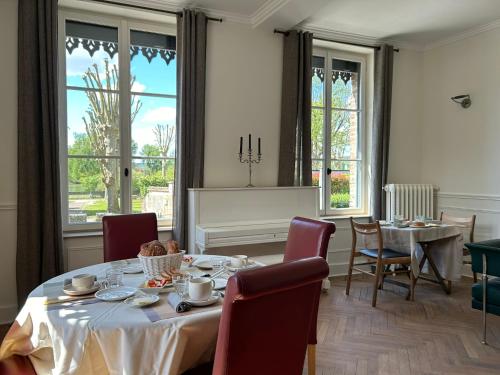 una sala da pranzo con tavolo, sedie e finestre di Villa du Vieux Château a Les Andelys
