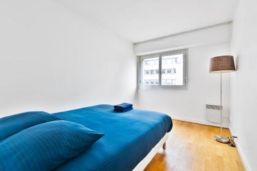 een blauw bed in een witte kamer met een raam bij Appartement Quartier Tour Eiffel 4 in Parijs