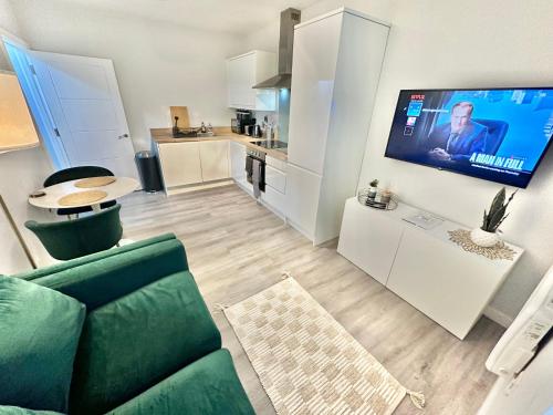 a living room with a green couch and a kitchen at Spacious One Bedroom Apartment - With Parking and WiFi - Town Centre Location - Gated Access - Walk to Beach! in Bournemouth