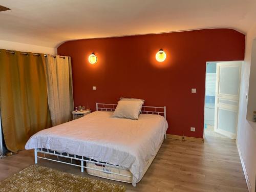 une chambre avec un lit et un mur rouge dans l'établissement Maison de ville Omaha Beach, à Le Molay-Littry