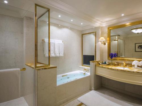 a bathroom with a tub and a sink and a mirror at Mövenpick Hotel Al Khobar in Al Khobar