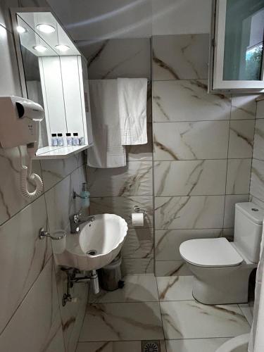 a white bathroom with a toilet and a sink at Nefeli Studios in Vathi, Mani