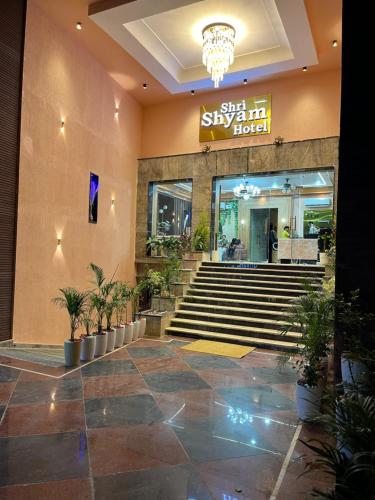 a lobby of a building with stairs and potted plants at Shri Shyam Hotel, Near Harkipauri in Haridwār