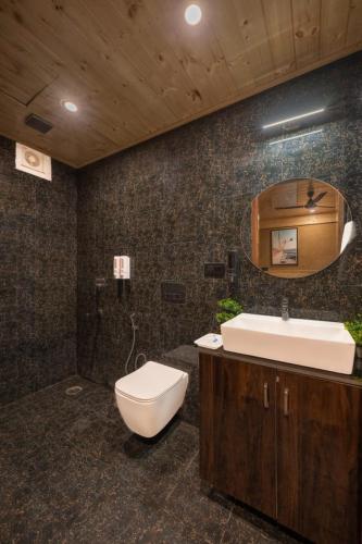 a bathroom with a toilet and a sink and a mirror at The Charvi Retreat by Exotic Stays in Shimla