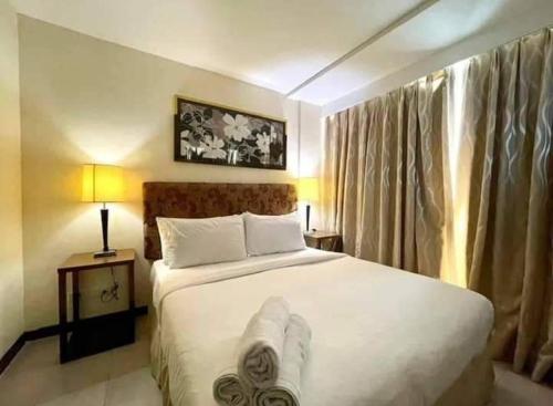 um quarto com uma cama grande e lençóis brancos em One Tagaytay Place Hotel Suites em Tagaytay