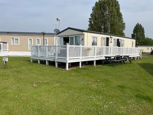 a mobile home with a porch and a picnic table at Seaview Caravan 2 Bedroom Sleeps 6 -WiFi -Smart Tv in Colchester