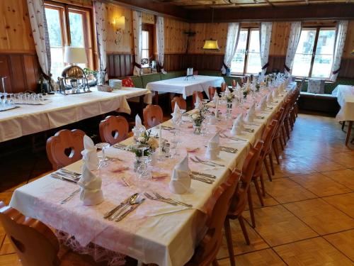 a row of tables in a room with white table settings at Hotel Schlosswirt in Großkirchheim