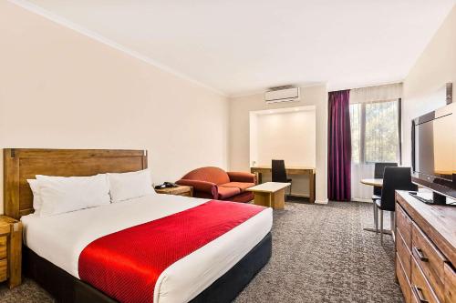um quarto de hotel com uma cama e uma televisão de ecrã plano em Quality Hotel Manor em Mitcham