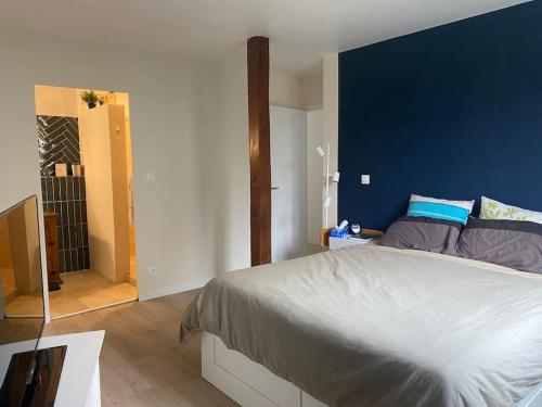 une chambre avec un grand lit avec un mur bleu dans l'établissement Grande maison familiale au calme, à Bouchemaine