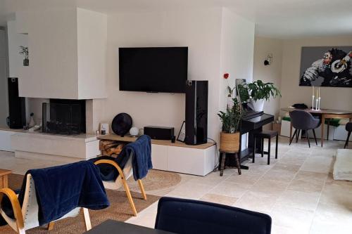 un salon avec une télévision à écran plat au mur dans l'établissement Grande maison familiale au calme, à Bouchemaine