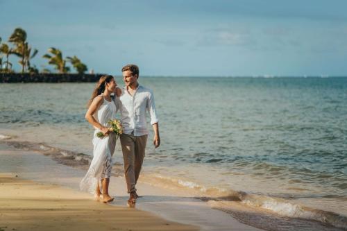 a bride and groom walking on the beach at Radisson Blu Azuri Resort & Spa in Roches Noires