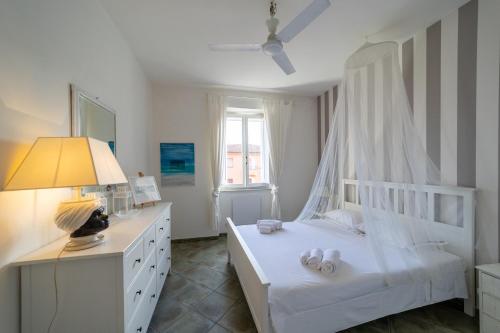 ein weißes Schlafzimmer mit einem weißen Bett und einem Fenster in der Unterkunft EasyTopStay - Porto Ercole Cosy Flat in Porto Ercole