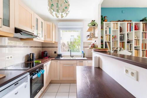 une cuisine avec des armoires en bois et un comptoir dans l'établissement Bel appartement avec terrasse et parking gratuit, à Massy