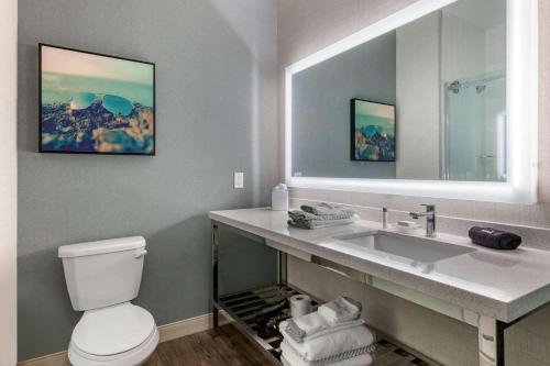 a bathroom with a sink and a toilet and a mirror at Cambria Hotel St Petersburg-Madeira Beach Marina in St. Pete Beach