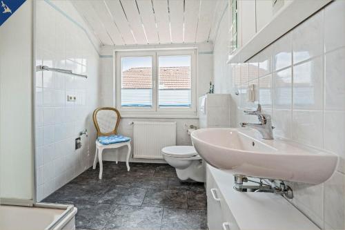 La salle de bains blanche est pourvue d'un lavabo et de toilettes. dans l'établissement Am Schulberg Ferienhaus Albatros, à Heringsdorf