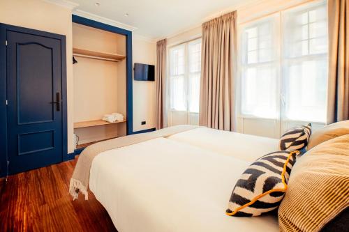 1 dormitorio con cama blanca y puerta azul en GETXO ROOMS, en Getxo