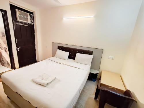 a small bedroom with a white bed and a black door at Hotel Red - Vasant Kunj in New Delhi
