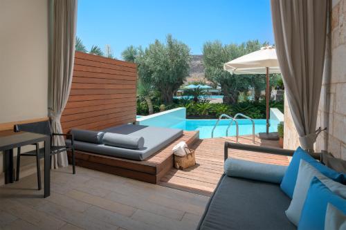 a patio with a bed and a swimming pool at Aquagrand Artistic Luxury Beach Resort - Adults Only in Líndos
