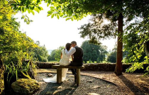 a bride and groom sitting on a park bench at The Upper House in Stoke on Trent