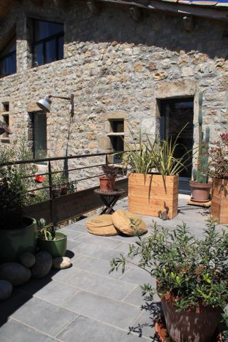 a patio with potted plants in front of a stone building at La Demeure des Maitres in Chirols