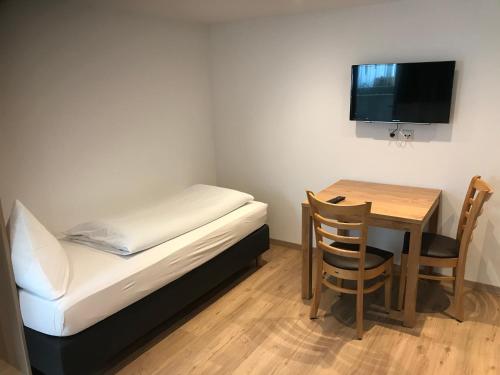 Kleines Zimmer mit einem Bett und einem Tisch mit einem TV. in der Unterkunft Zimmerding in Erding