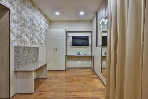 a large kitchen with white cabinets and a television at Hotel Cama in Chandīgarh