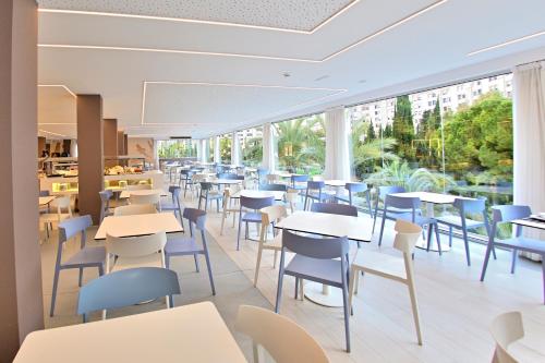 a restaurant with tables and chairs and windows at Prince Park in Benidorm