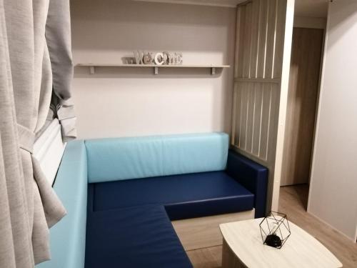 un canapé bleu dans une pièce avec une table dans l'établissement Charmant mobil-home cosy 149, à Narbonne