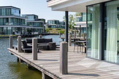 a wooden dock with chairs and tables on the water at Dormio Harbour Village in Arnemuiden
