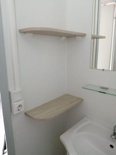 une salle de bain blanche avec un lavabo et un miroir dans l'établissement Charmant mobil-home cosy 149, à Narbonne