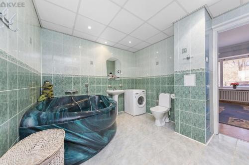 een groene betegelde badkamer met een bad en een toilet bij Elegance in the Heart of Tallinn - 150 m2 luxurious apartment with 4 large bedrooms! in Tallinn