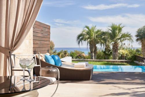 a patio with a couch and a glass of wine at Aquagrand Artistic Luxury Beach Resort - Adults Only in Líndos