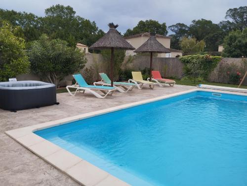 une piscine avec des chaises longues et une piscine dans l'établissement Bienvenue au pied des Alpilles, à Saint-Étienne-du-Grès