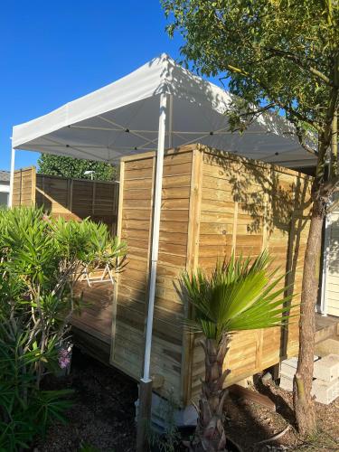 une pergola en bois avec un parasol dans une cour dans l'établissement Europcamping, à Fréjus