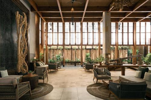 - un hall avec des chaises, des tables et une grande fenêtre dans l'établissement Dinso Resort & Villas Phuket, Vignette Collection, an IHG Hotel, à Patong Beach