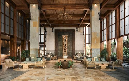 a lobby with tables and chairs and a chandelier at Dinso Resort & Villas Phuket, Vignette Collection, an IHG Hotel in Patong Beach