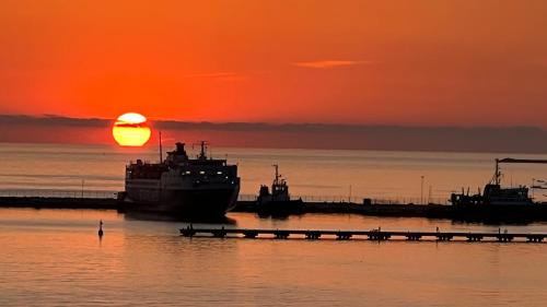 a boat is docked at a dock with the sunset at Marina Premium Hotel & Apartments in Vlorë