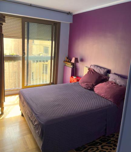 une chambre avec un lit aux murs violets et une fenêtre dans l'établissement Chambre d'hôtes au calme, à Paris