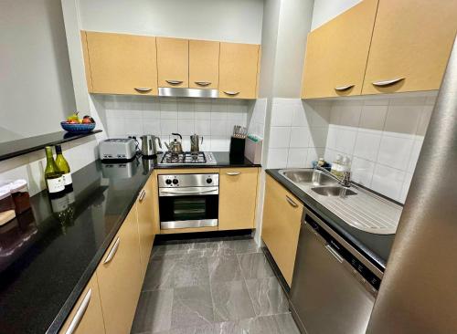 a small kitchen with a stove and a sink at Ocean View Private Cronulla Apartment in Cronulla