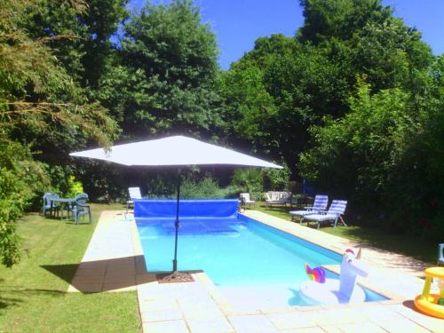 - une piscine avec un parasol à côté d'une cour dans l'établissement The Nightingales, à Laniscat