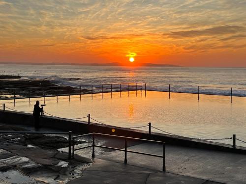 a person walking on the beach at sunset at Ocean View Private Cronulla Apartment in Cronulla