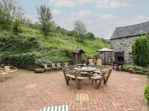 a patio with a table and chairs and a stone building at Pengwern in Pennant-Melangell